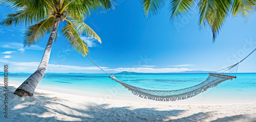 Fototapeta Naklejka Na Ścianę i Meble -  a hammock with a palm tree hanging on a white and blue beach, exotic fantasy landscapes. Tropical beach background, summer relax landscape.  Luxury Vacation and summer holiday concept. wide panorama
