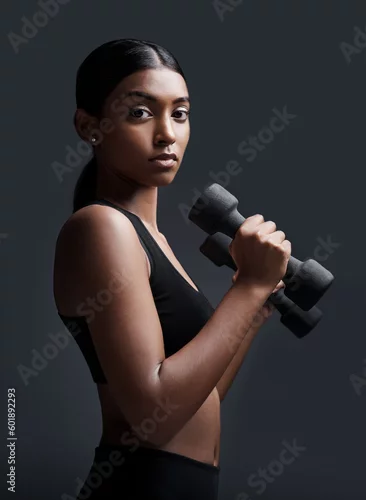 Obraz Serious, portrait and woman with dumbbells for workout in studio isolated on a black background. Strong, bodybuilder and Indian female athlete weightlifting for muscle, training and fitness exercise.
