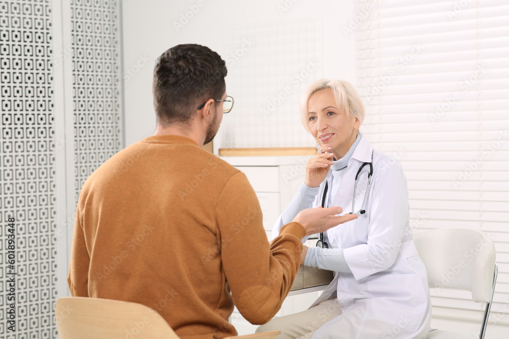 Doctor consulting patient at table in clinic Doctor consulting patient at table in clinic