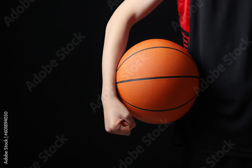 Boy with basketball ball on black background, closeup. Space for text