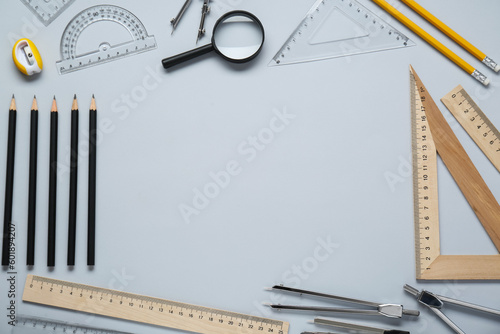 Flat lay composition with different rulers and compasses on light grey background. Space for text