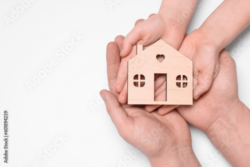 Home security concept. Family holding house model on white background, top view with space for text