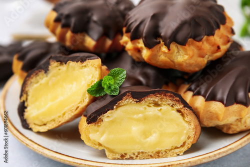 Delicious profiteroles with chocolate spread and cream on plate, closeup