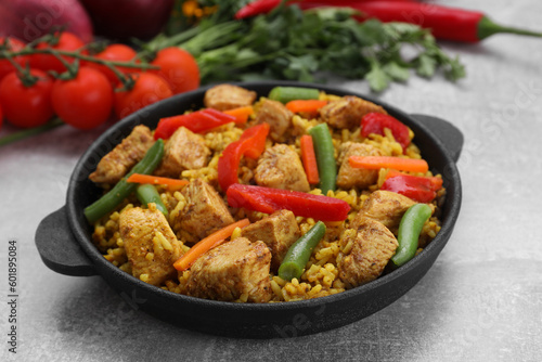 Serving pan of delicious rice with chicken and vegetables on light grey table, closeup