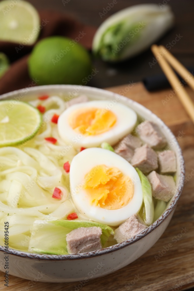 Bowl of delicious rice noodle soup with meat and egg on wooden board, closeup Bowl of delicious rice noodle soup with meat and egg on wooden board, closeup