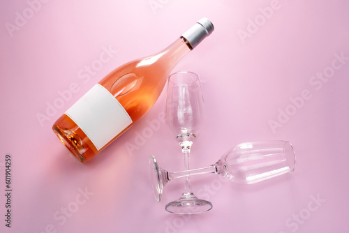 Wine bottle mockup  unopened bottle of rose wine and two glasses on pink background  top view  copy space  flat lay