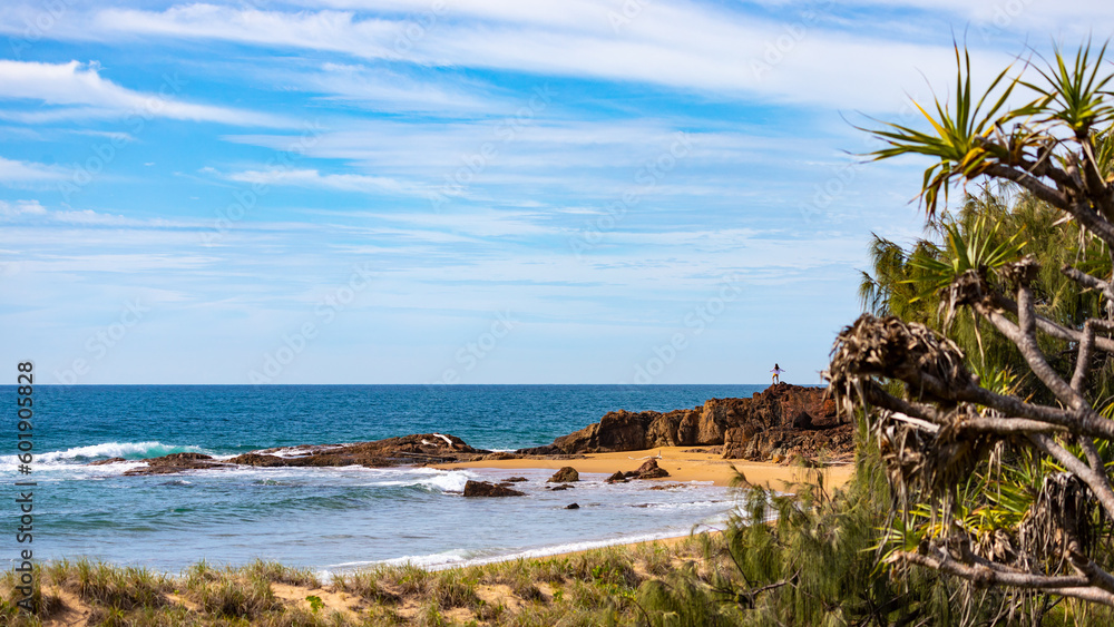 little silhouette of long haired girl standing on the rocks and gazing at the sea at wreck rock beach in deepwater national park near agnes water, queensland, australia