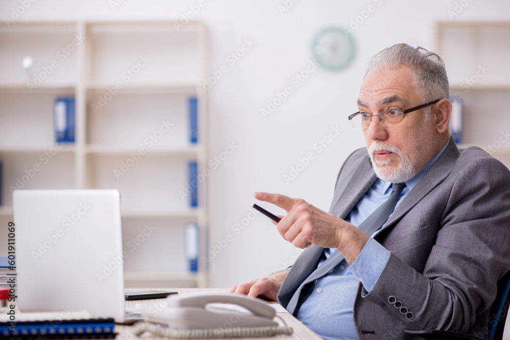 Old male employee working in the office Old male employee working in the office