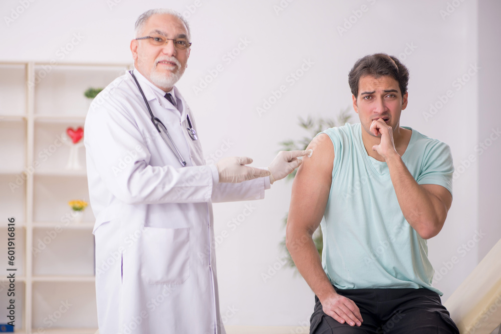 Young male patient visiting old male doctor in vaccination conce Young male patient visiting old male doctor in vaccination conce