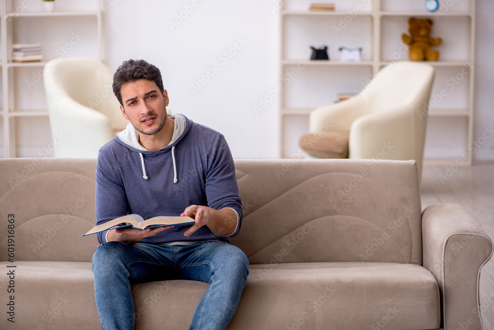 Young male student reading book at home Young male student reading book at home