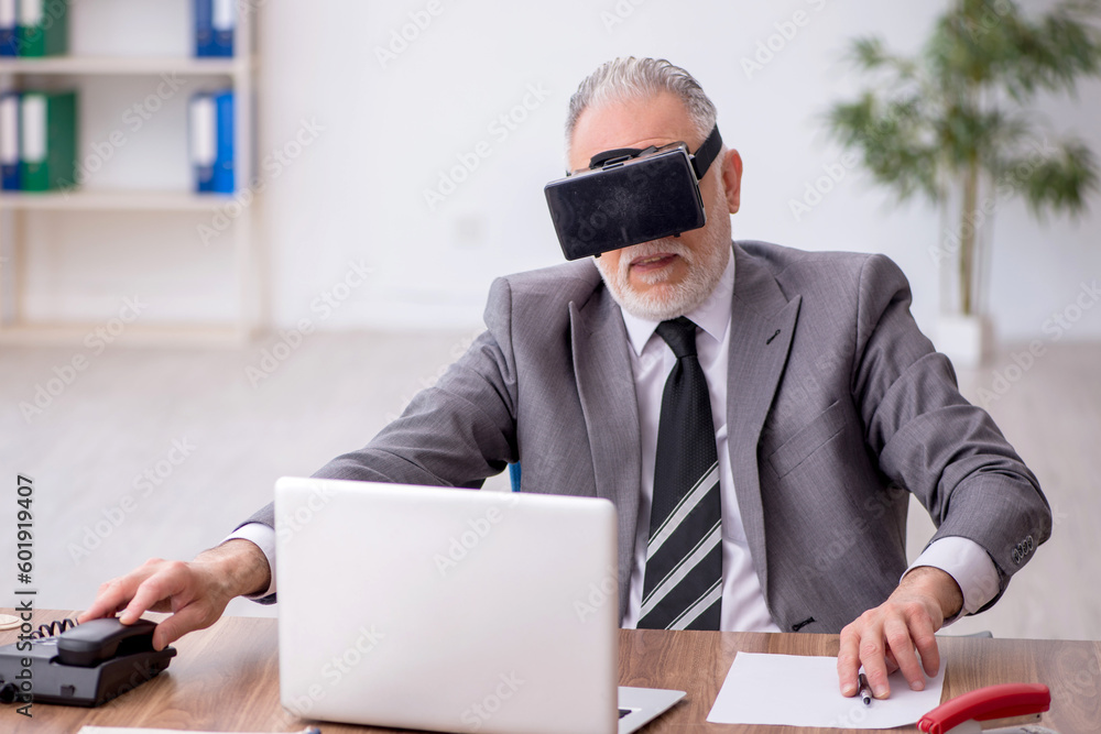 Old male employee enjoying virtual glasses at workplace Old male employee enjoying virtual glasses at workplace