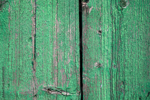 Wood texture with green flaked paint. Peeling paint on weathered wood. Old cracked paint pattern on rusty background. Chapped paint on an old wooden surface