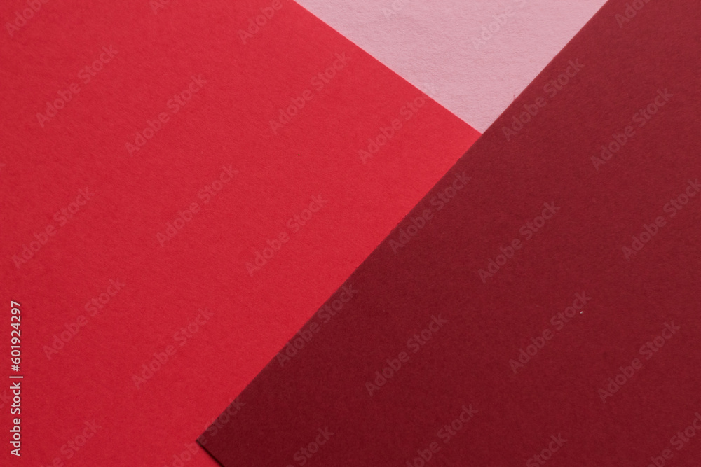 Paper in three shades of red lies on the table, creating a geometric composition