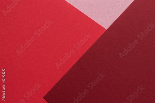 Paper in three shades of red lies on the table, creating a geometric composition