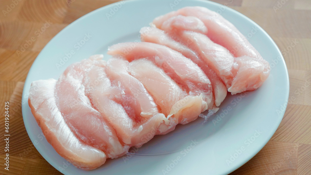 raw sliced chicken meat on a white plate