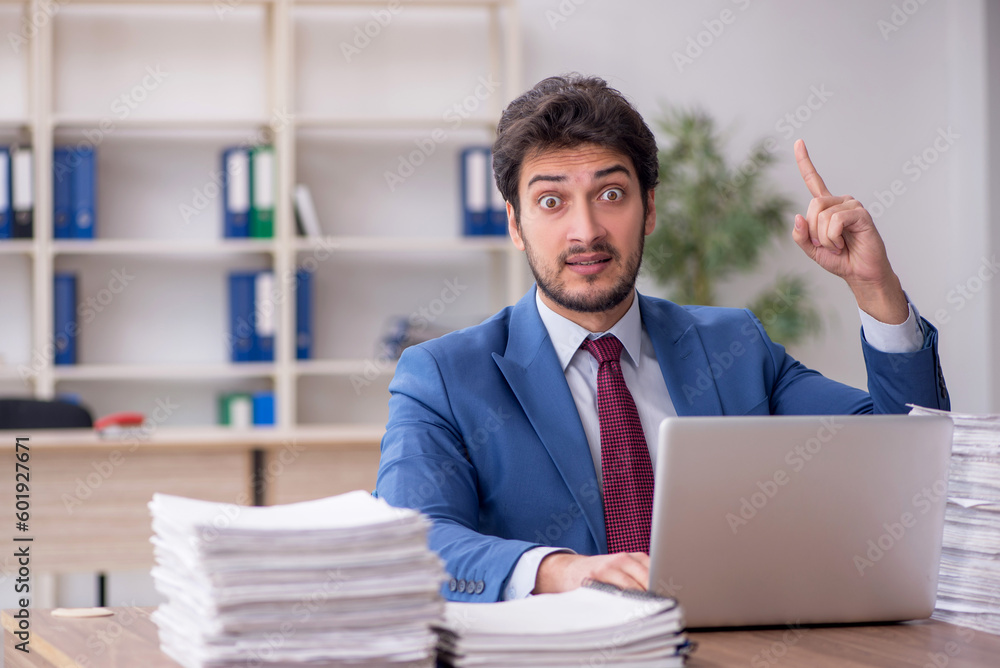 Young male employee and too much work in the office Young male employee and too much work in the office