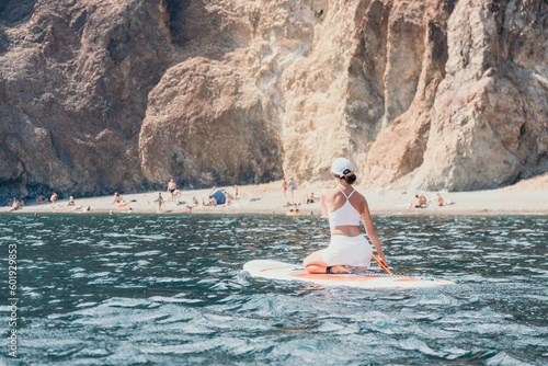 Woman sup yoga. Happy sporty woman practising yoga pilates on paddle sup surfboard. Female stretching doing workout on sea water. Modern individual female hipster outdoor summer sport activity. © panophotograph