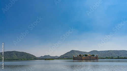 The ancient flooded palace of Jal Mahal in the Man Sagar Lake. The top floor of the building rises above the water. Weathered walls, towers, domes, trees on the roof are visible. India. Jaipur photo