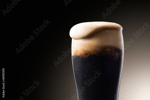 黒ビール、水滴のついたグラスから泡が溢れる冷えたビール photo