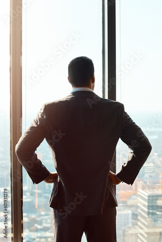 Thinking, building window and a business man with ideas, vision or plan for cityscape. Professional male entrepreneur with hands on hips for dream, growth and corporate development from behind © Grady Reese/peopleimages.com