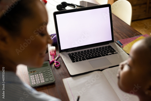 Schilderij op canvas African american mother helping daughter with schoolwork using laptop at home, c