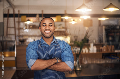 Coffee shop, waiter and portrait of African man in restaurant for service, working and crossed arms in cafe. Small business owner, bistro startup and male barista smile in cafeteria ready to serve