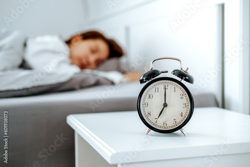 Close up Clock on the bed Asian woman wake up and disturbed by alarm clock early morning