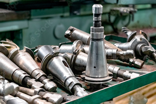A set of milling cutters on a rack near a lathe. Metalworking cutting mills for CNC machines. Industrial processing of metal products with a cutting tool on an automatic lathe.