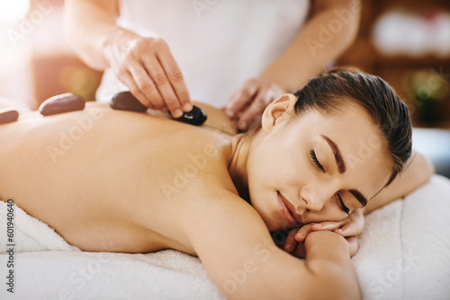 Therapy, relax and woman getting a hot stone back massage at spa for luxury, calm and natural self care. Beauty, body care and tranquil female person sleeping while doing rock body treatment at salon