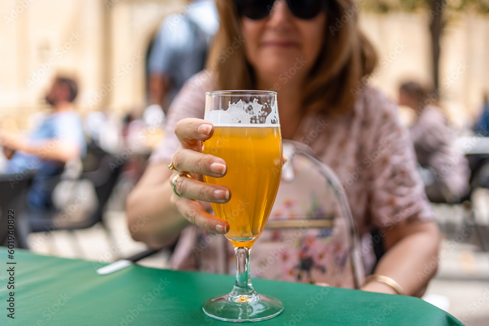 Glass of beer held by the hand of a woman on a terrace of a bar on the street, Spain.