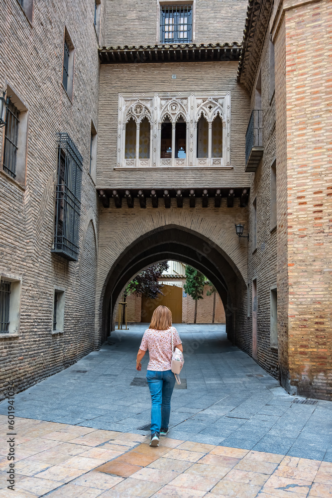 Woman strolling among the beautiful medieval buildings of the old town of the city of Zaragoza, Spain.