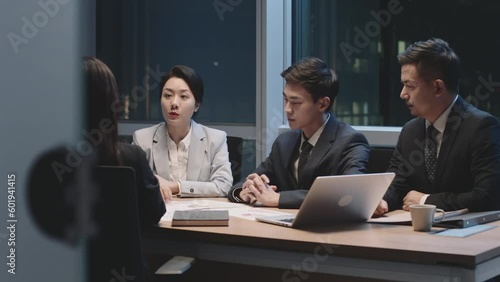 group of asian corporate executives working overtime meeting in office discussing business strategy