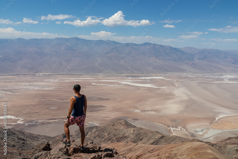 Fototapeta premium Rear view of man overlooking the Salt Badwater Basin and Panamint Mountains seen from Dante's View in Death Valley National Park, California, USA, America. Aerial scenic view on dry desert landscape