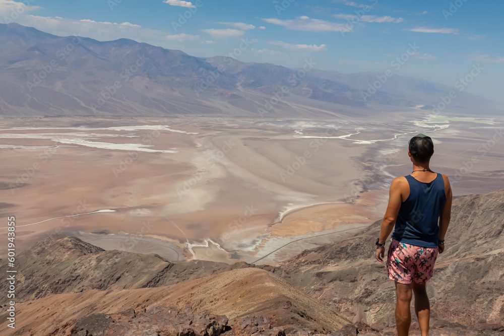 Rear view of man overlooking the Salt Badwater Basin and Panamint Mountains seen from Dante's View in Death Valley National Park, California, USA, America. Aerial scenic view on dry desert landscape