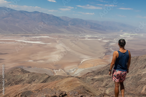 Rear view of man overlooking the Salt Badwater Basin and Panamint Mountains seen from Dante's View in Death Valley National Park, California, USA, America. Aerial scenic view on dry desert landscape
