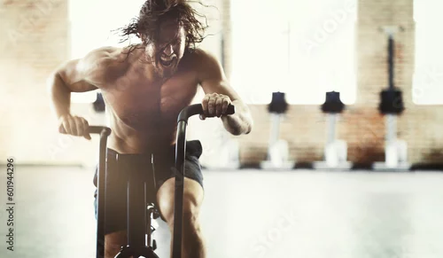 Obraz Workout, fitness and man on elliptical in gym for health, training or exercise. Sports, motivation and determined male shouting on cross trainer bike for exercising, cardio and cycling for strength.