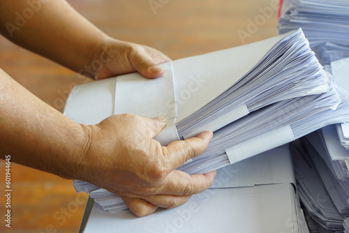 Closeup hands hold stack of used paper to recycle or combine to use next time to print out both sides of paper. Concept, eco friendly activity for environment, reuse paper.             © Sanhanat