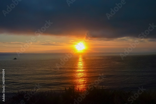 Watching sunset from Bixby Creek Bridge on coastline of Big Sur, Monterey county, California, USA, America. View of horizon of Pacific Ocean. Sun is reflecting in calm sea. Vibrant clouds in the sky © Chris