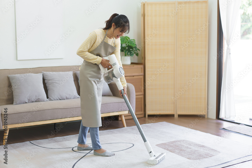 Maid using cordless vacuum cleaner to vacuuming and cleaning the dust on the carpet in home Maid using cordless vacuum cleaner to vacuuming and cleaning the dust on the carpet in home