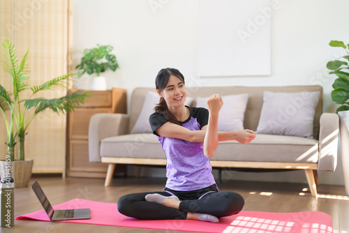 Sporty woman watching yoga training online and doing stretching arms to exercise for yoga at home
