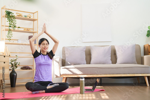 Sporty woman meditating to practice yoga exercise while raise hands to doing yoga with namaste pose