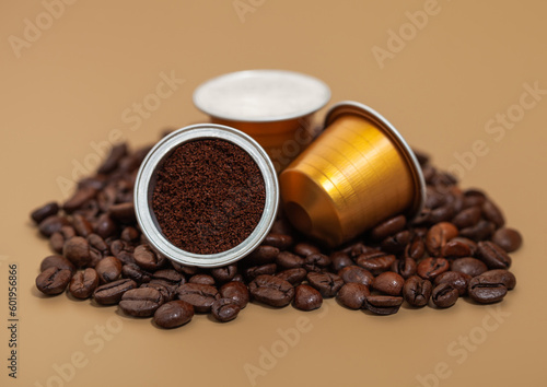 Capsules with ground coffee on fresh raw aroma beans on beige background. photo
