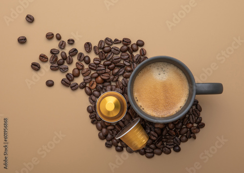 Coffee cup with fresh raw beans and coffee capsules on beige background. photo