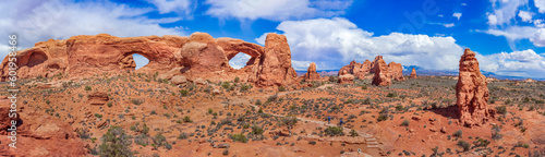 Panoramic view of North Window  South Window  and Turret Arch with beautiful clouds in the sky  small figures of people in the frame emphasize the scale and beauty of this majestic creation  Moab  USA