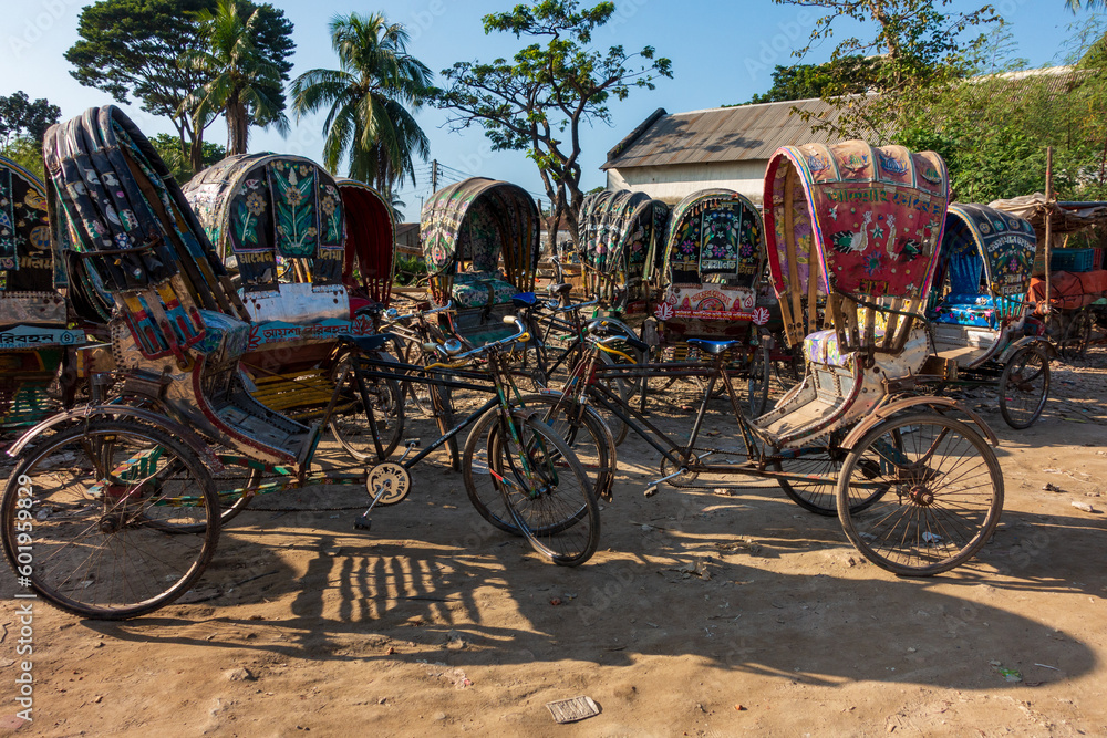 Colorful rickshaws lined up on the unpaved ground.