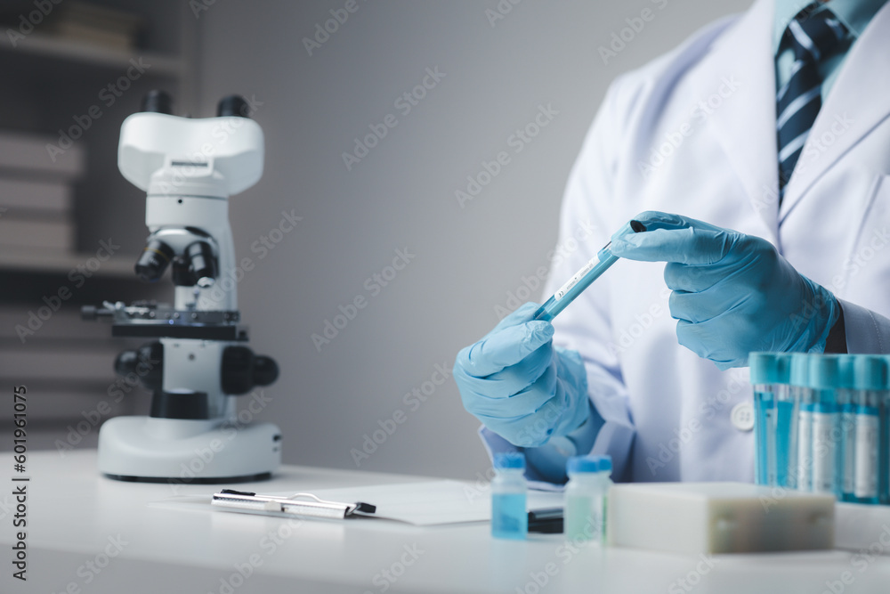 Lab assistant, medical scientist, chemistry researcher holds a glass tube through a chemical test tube, does a chemical experiment and examines a patient's sample. Medicine and research concept. Lab assistant, medical scientist, chemistry researcher holds a glass tube through a chemical test tube, does a chemical experiment and examines a patient's sample. Medicine and research concept.
