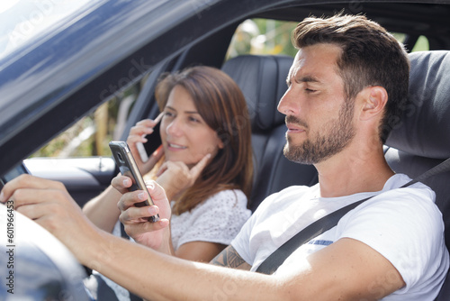 couple in car both using cellphones while driving