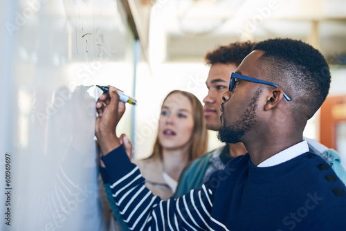 Diversity, students writing on whiteboard and in classroom of school building. Problem solving or formula, brainstorming or presentation and people write on board in class of college or university