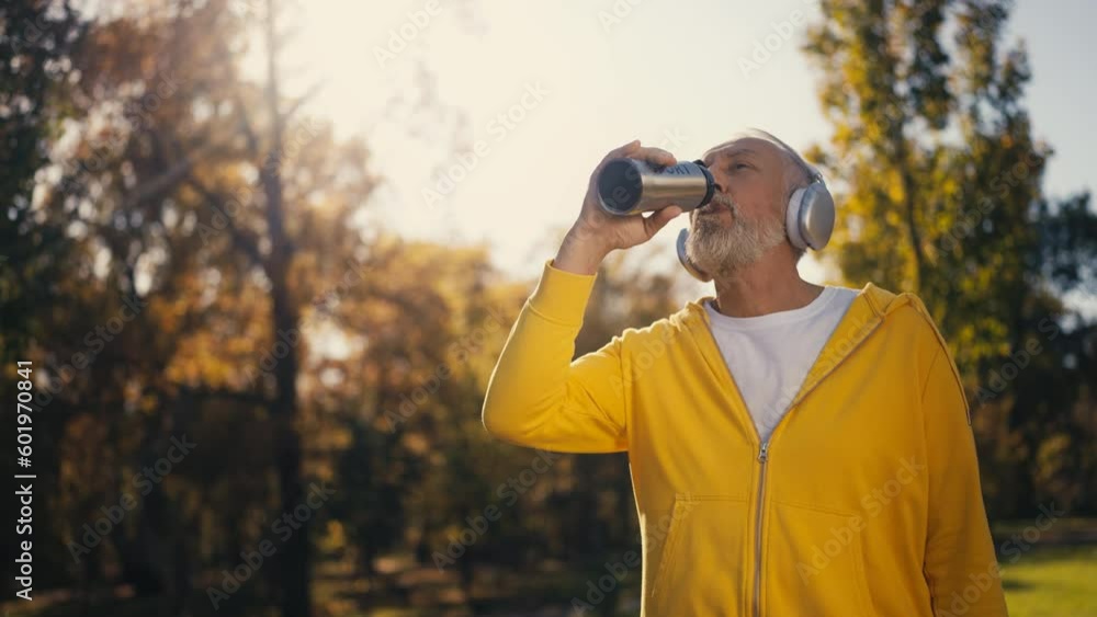 Senior man in sportswear drinking water after working out outdoor, water balance Senior man in sportswear drinking water after working out outdoor, water balance