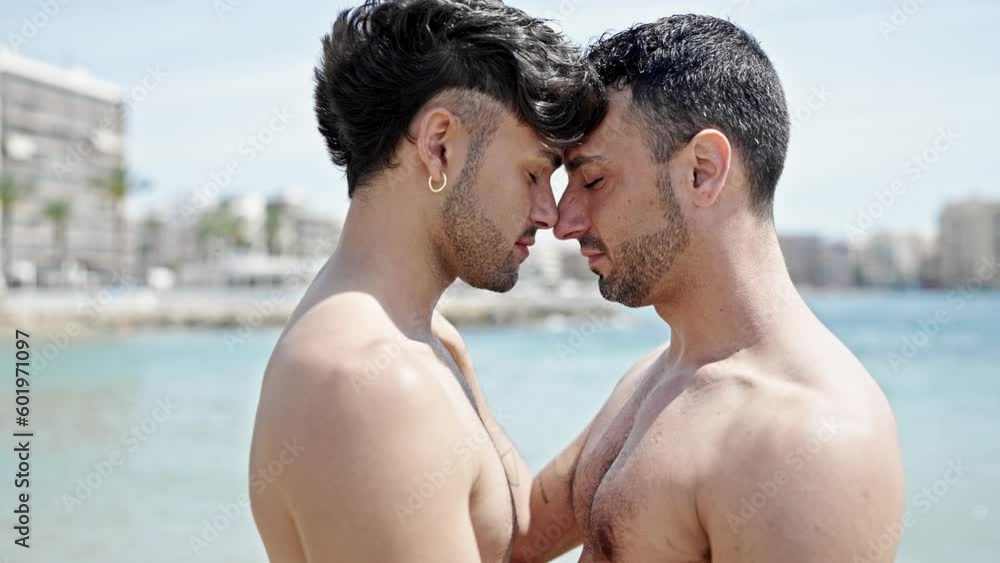Two men tourist couple smiling confident standing together at beach Two men tourist couple smiling confident standing together at beach